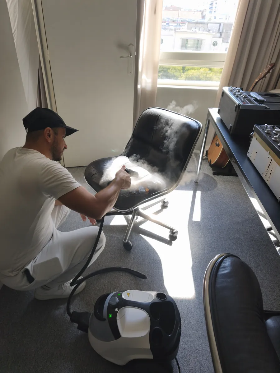 Technicien appliquant de la vapeur sèche sur une chaise de bureau en cuir lors d'un traitement punaises de lit à Paris 19e