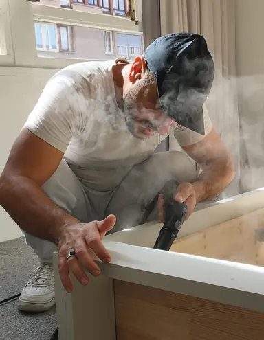 Technicien Office Dératisation France appliquant la vapeur sèche à 180 °C dans l'angle d'un sommier pour détruire les punaises de lit et leurs œufs