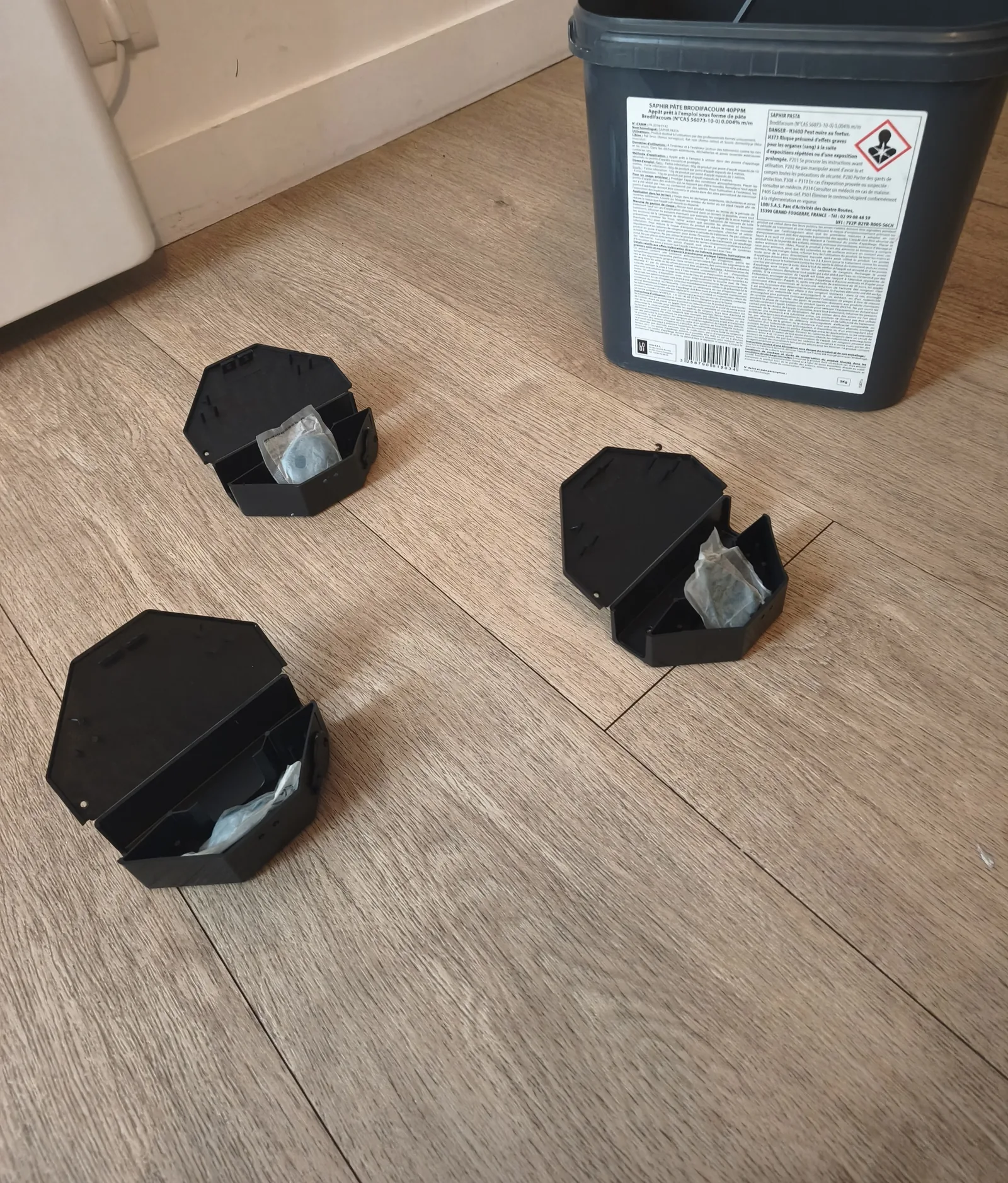 Three locked bait stations opened to show the secured bait sachets before placement, mouse control in a short-term rental in Paris 17e